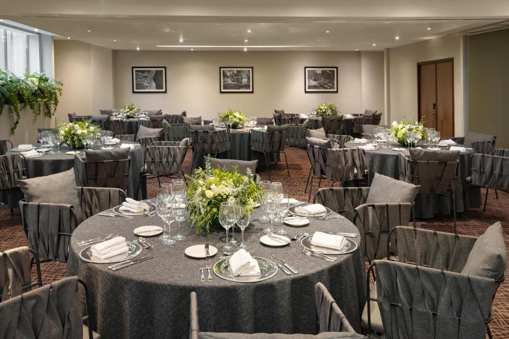 A banquet dining room set with round tables, floral centerpieces, and full place settings.