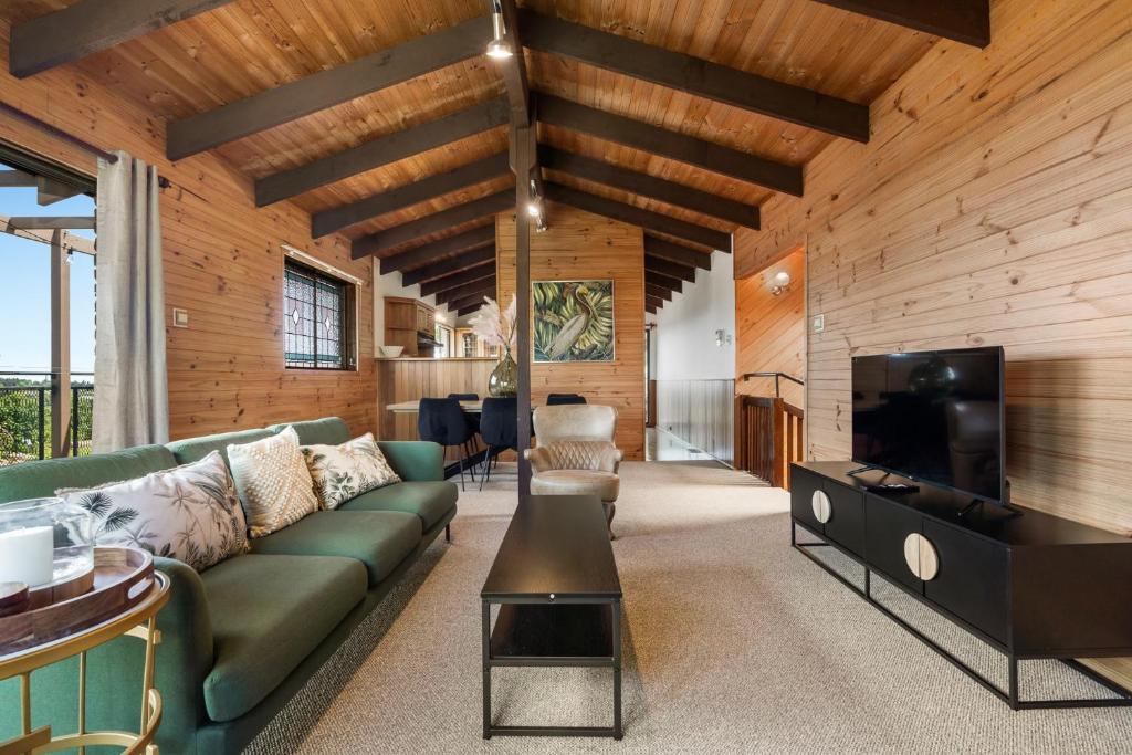 ein Wohnzimmer mit einem grünen Sofa und einem Flachbild-TV in der Unterkunft Sunset Lodge - Breathtaking Views in Orange