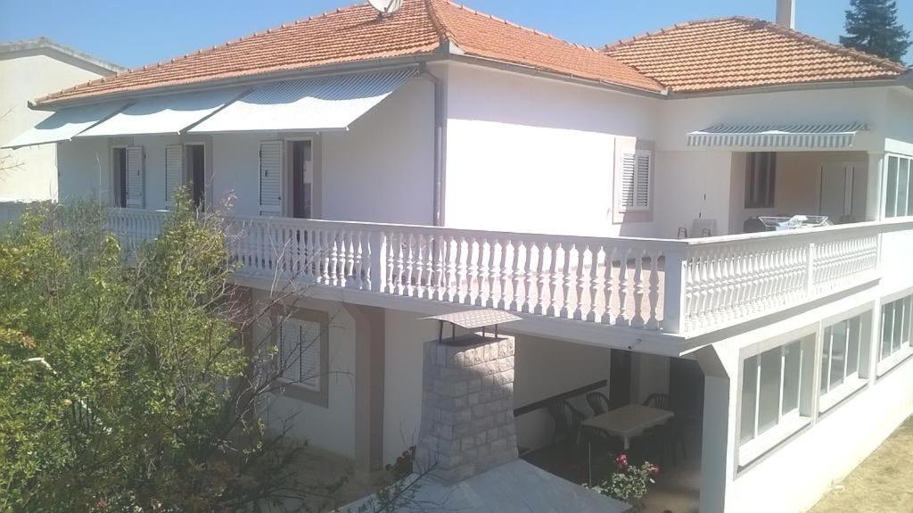 Dieses weiße Haus verfügt über einen Balkon mit einer Veranda. in der Unterkunft Apartments by the sea Biograd na Moru, Biograd - 21597 in Biograd na Moru
