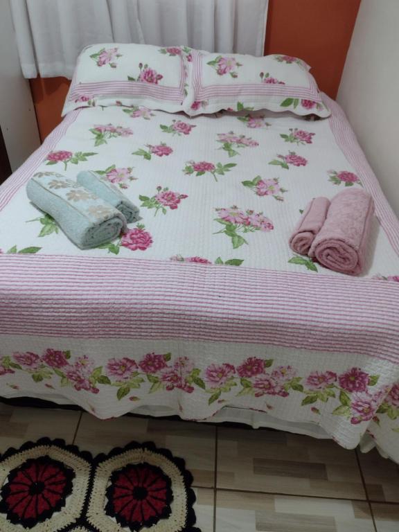 Una cama rosa y blanca con flores rosas. en Chácara pão de açúcar, en Bueno Brandão