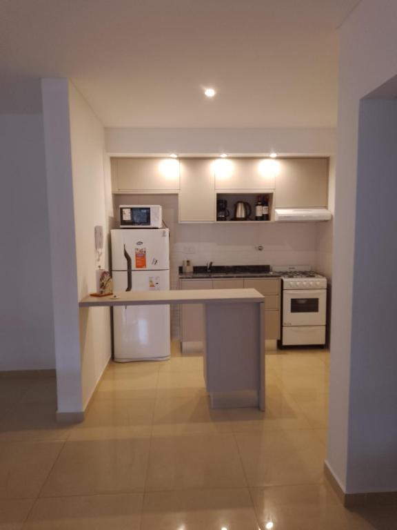 a kitchen with a counter top and a white refrigerator at Departamento a estrenar GALO VII in San Bernardo