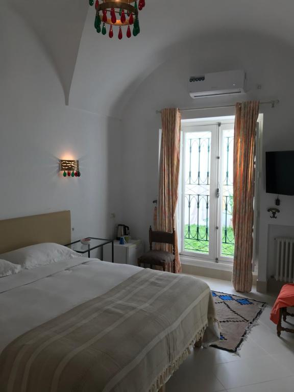 a bedroom with a bed and a large window at Dar Esma in La Marsa