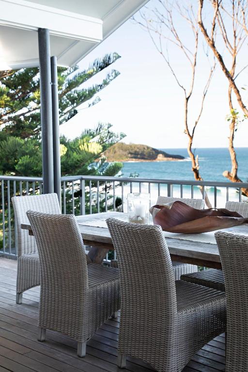 a wooden table and chairs on a deck with the ocean at Kalinda in Mollymook