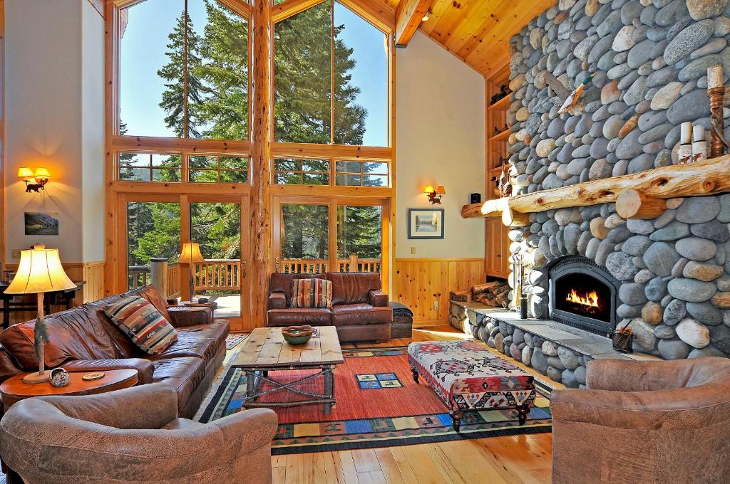 a living room with a large stone fireplace at Sierra Crest at Palisades Tahoe - Secluded Luxury 5BR 5 BA w Wood Fireplace in Olympic Valley