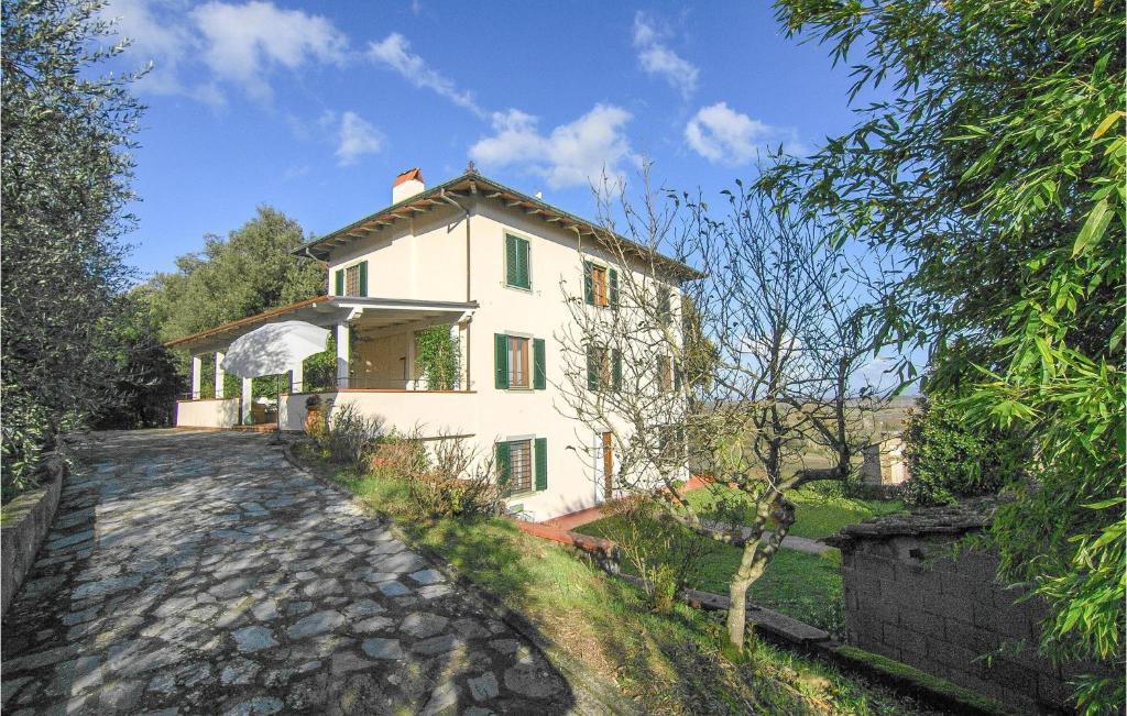 une maison blanche avec des fenêtres vertes et une allée en pierre dans l'établissement 5 Bedroom Nice Home In Castelvecchio Di Comp,, à Castelvecchio