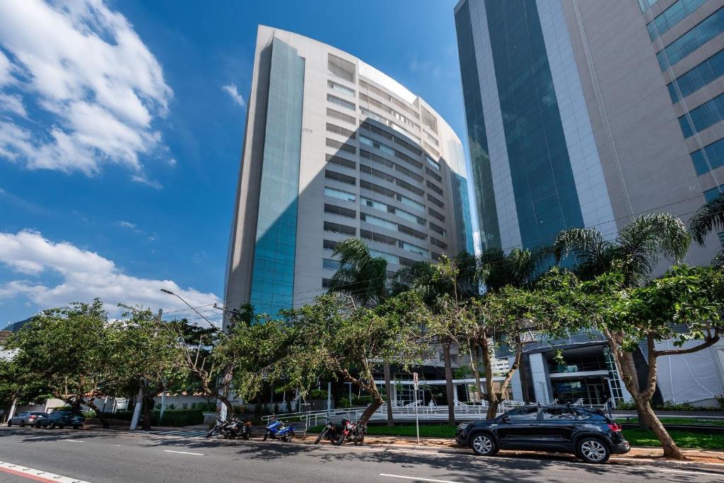 een auto geparkeerd voor een hoog gebouw bij Conforto e Praticidade em SP in Sao Paulo