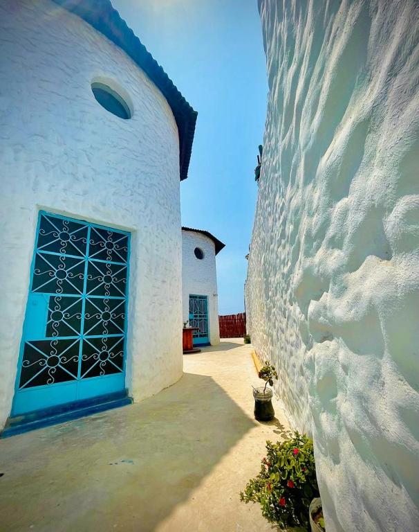 a white building with a blue door and a wall at Huanchaco Domes in Huanchaco