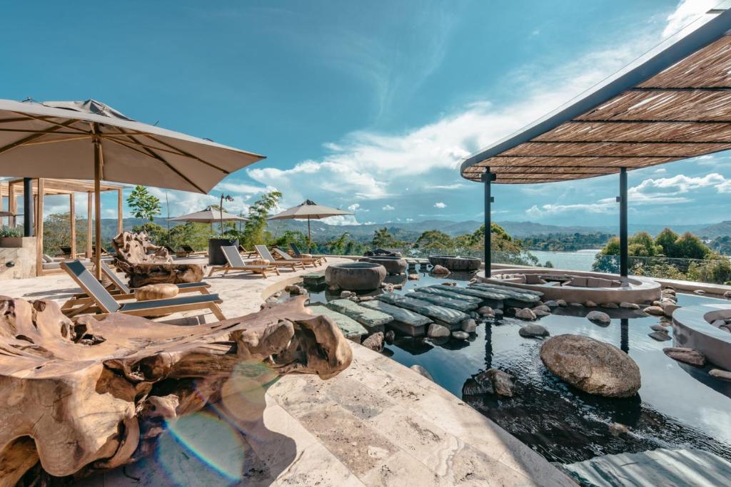 a resort with a pool with chairs and umbrellas at The Brown, Guatape in Guatapé