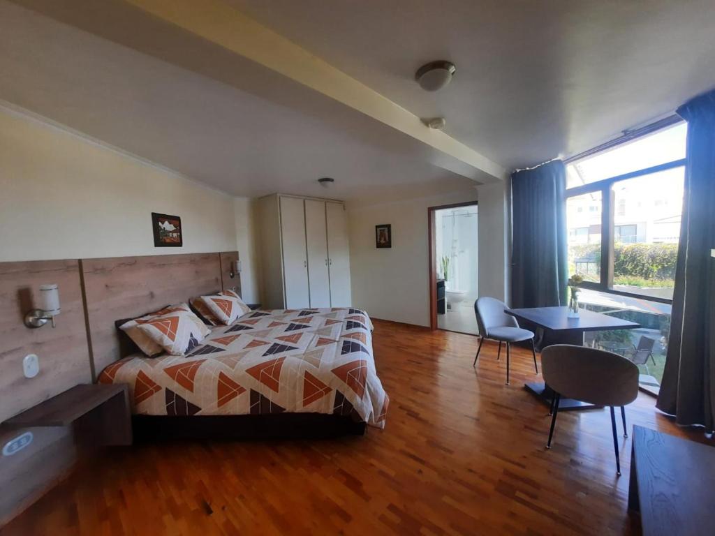 um quarto com uma cama, uma mesa e cadeiras em Hotel Rincon Aleman em Riobamba