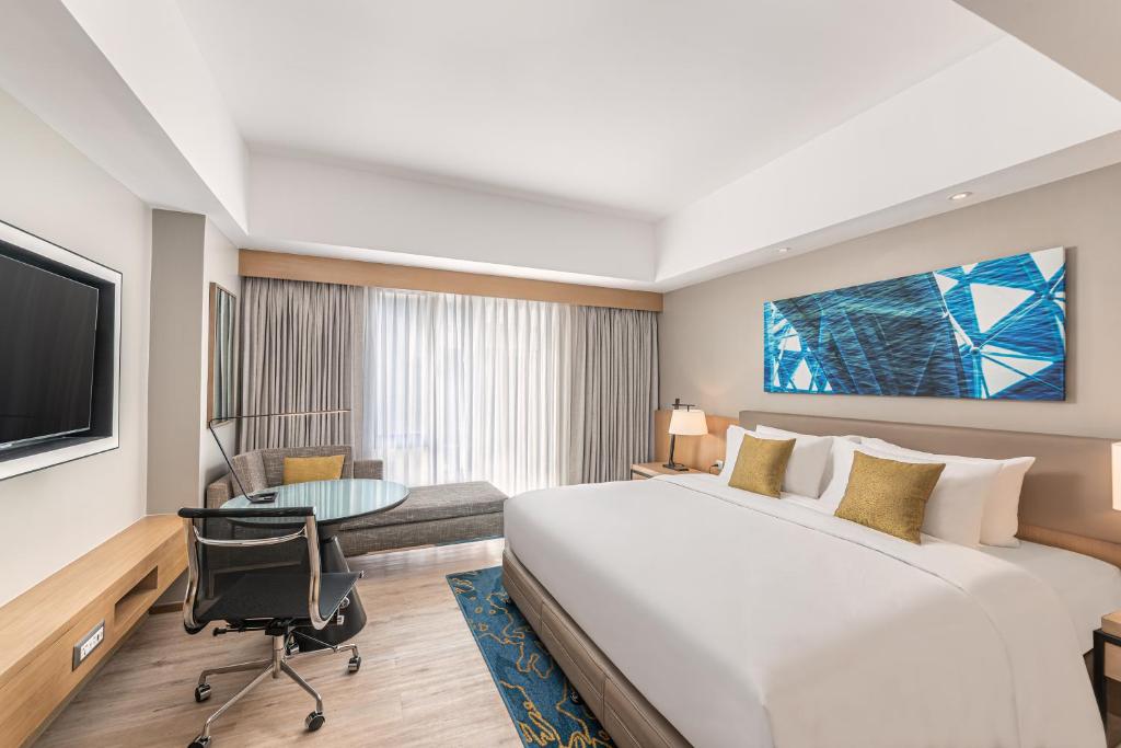 um quarto de hotel com uma cama grande e uma secretária em Seda Manila Bay em Manila