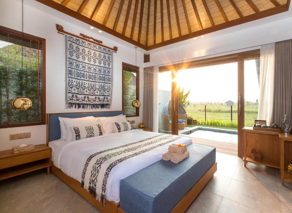 a bedroom with a bed with a teddy bear sitting on it at Suga Estate - Rice Field View Villas in Ubud