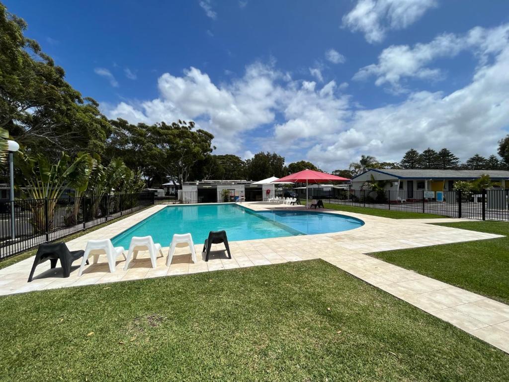 a swimming pool with two chairs and a table at Shelly Beach Holiday Park in The Entrance
