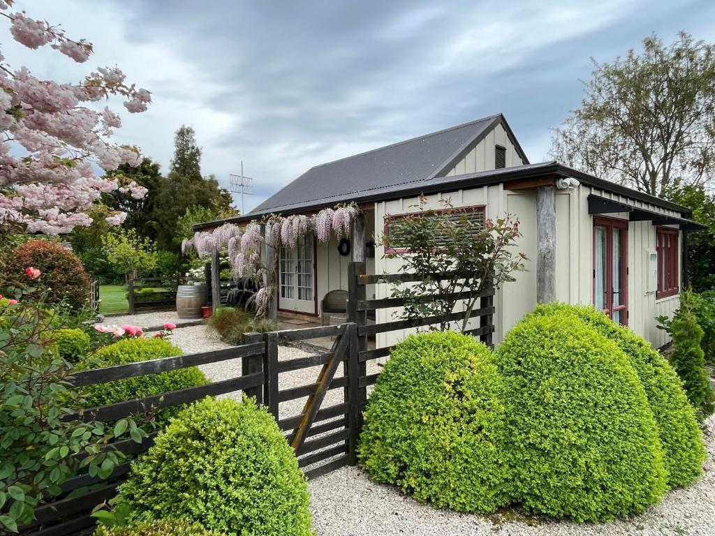 une petite maison avec une clôture et des fleurs dans l'établissement Tasman Village Cottage, à Tasman