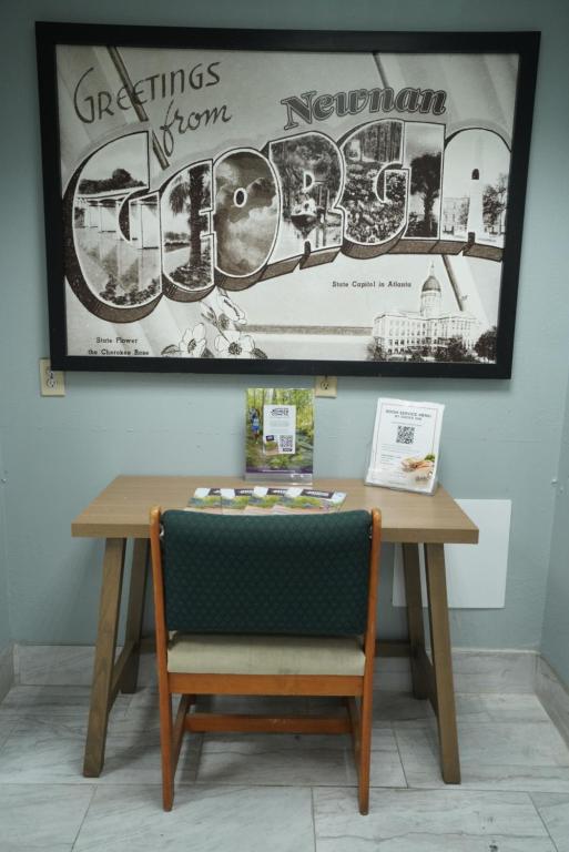 a table with a chair and a sign on the wall at Red Carpet Inn & Suites in Newnan