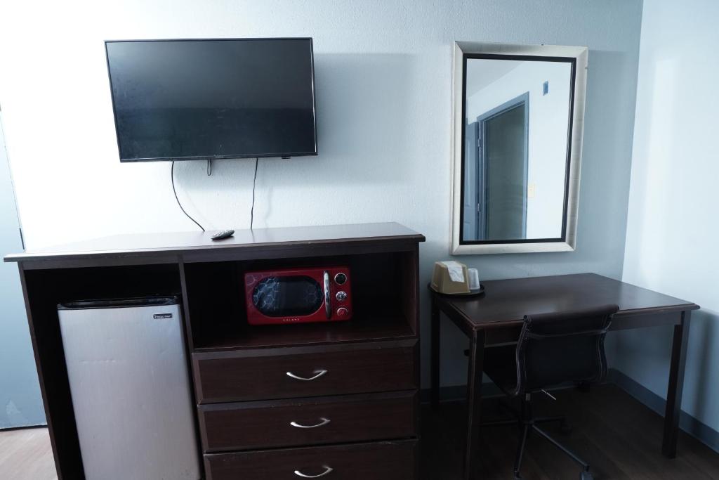 a room with a dresser with a tv and a desk at Red Carpet Inn & Suites in Newnan