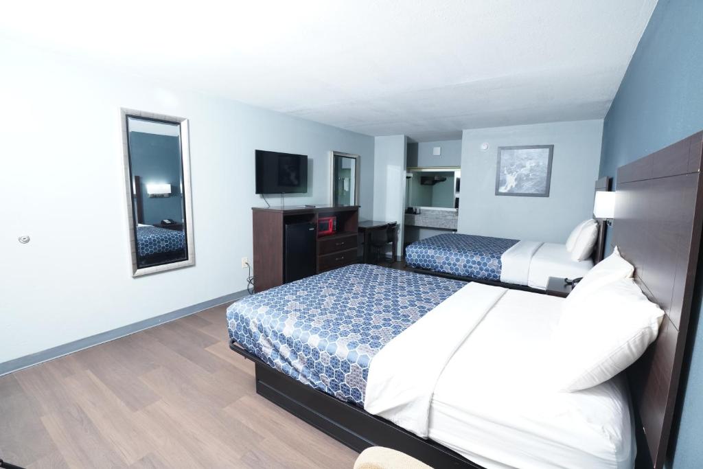 a hotel room with two beds and a television at Red Carpet Inn & Suites in Newnan