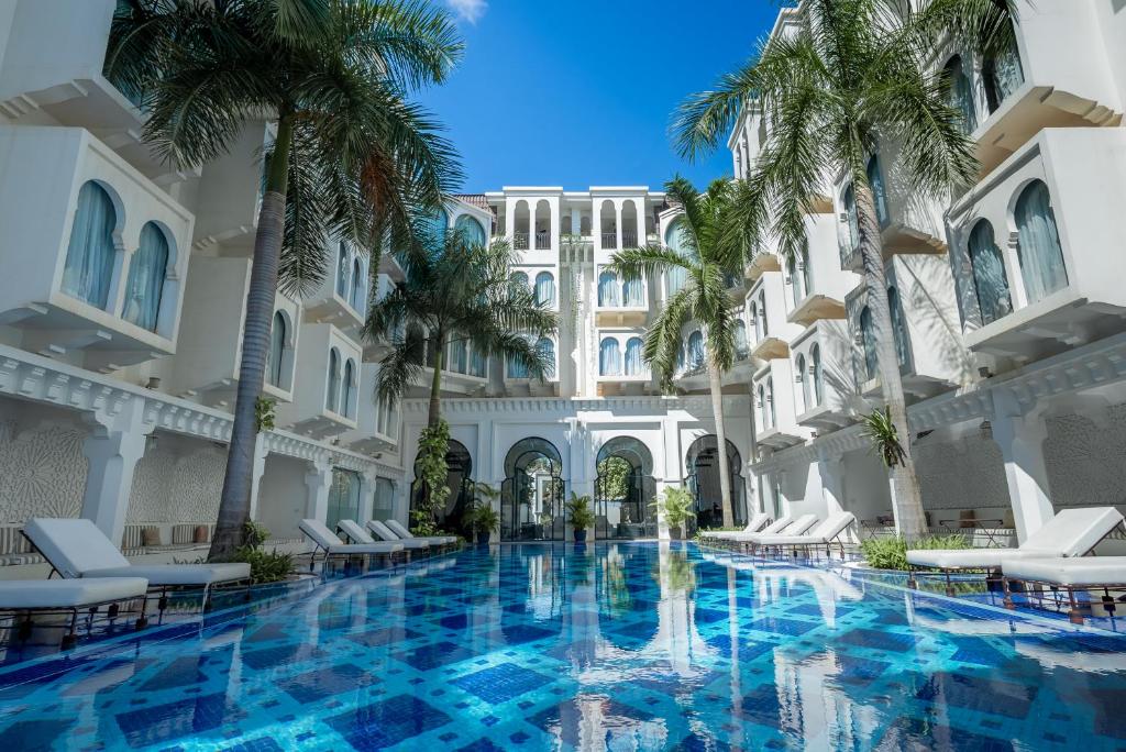 una piscina en el patio de un hotel con palmeras en Sarai Resort & Spa and The Wander, en Siem Reap