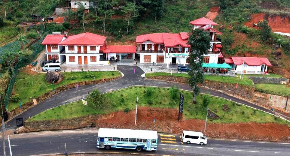 a bus driving down a road in front of a house at Nature First Hotel in Nuwara Eliya