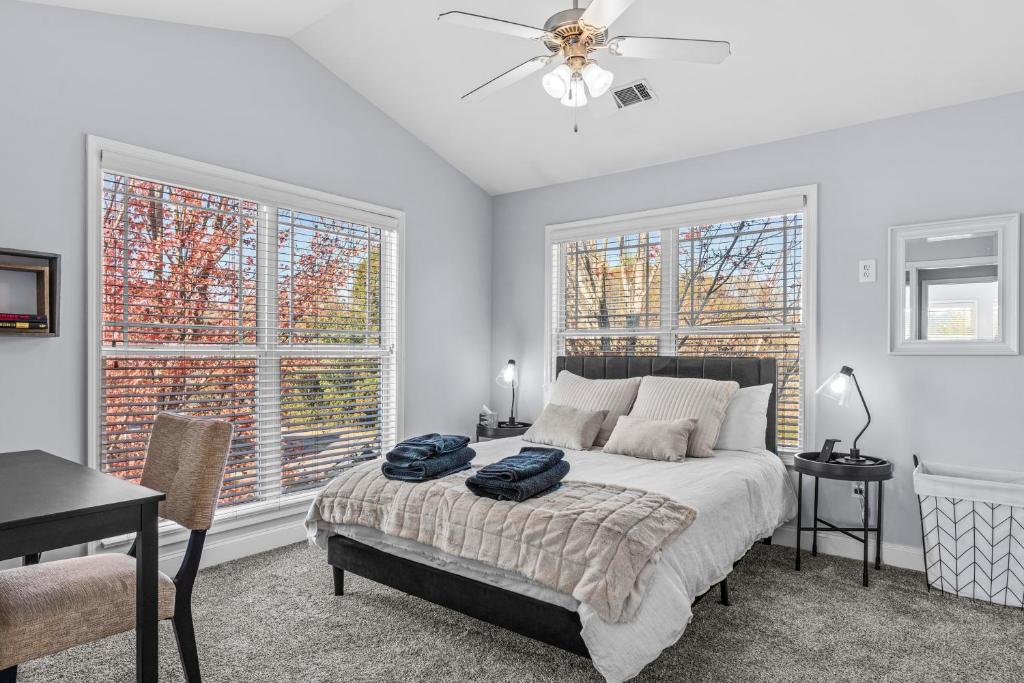 a bedroom with a bed with a ceiling fan and two windows at Whitehall Dawg Den - Right by North Oconee River! in Athens
