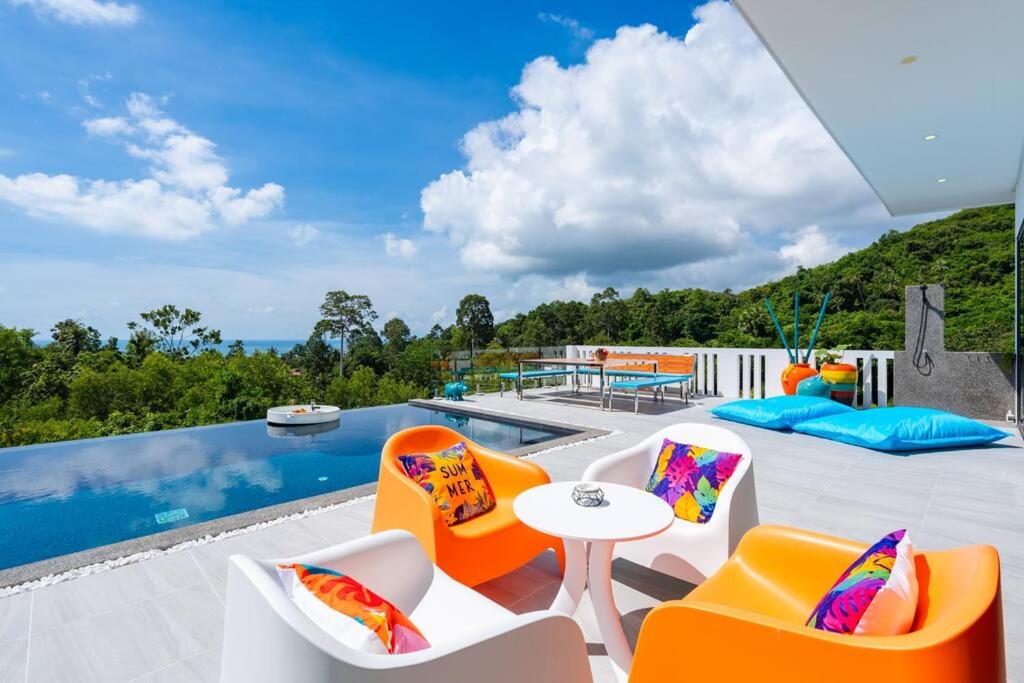 um pátio com cadeiras laranjas e brancas e uma piscina em Nelumbo Villa - Lamai Seaview - 4 bedroom em Nathon Bay