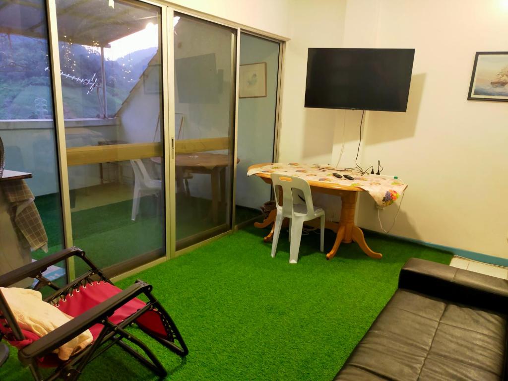 a living room with a table and green carpet at R2L5Y Room 1 with balcony and bathroom in Bentong