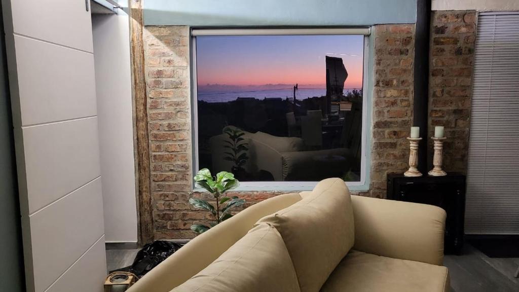 uma sala de estar com um sofá e uma grande janela em Seaview Happy place em Bettyʼs Bay