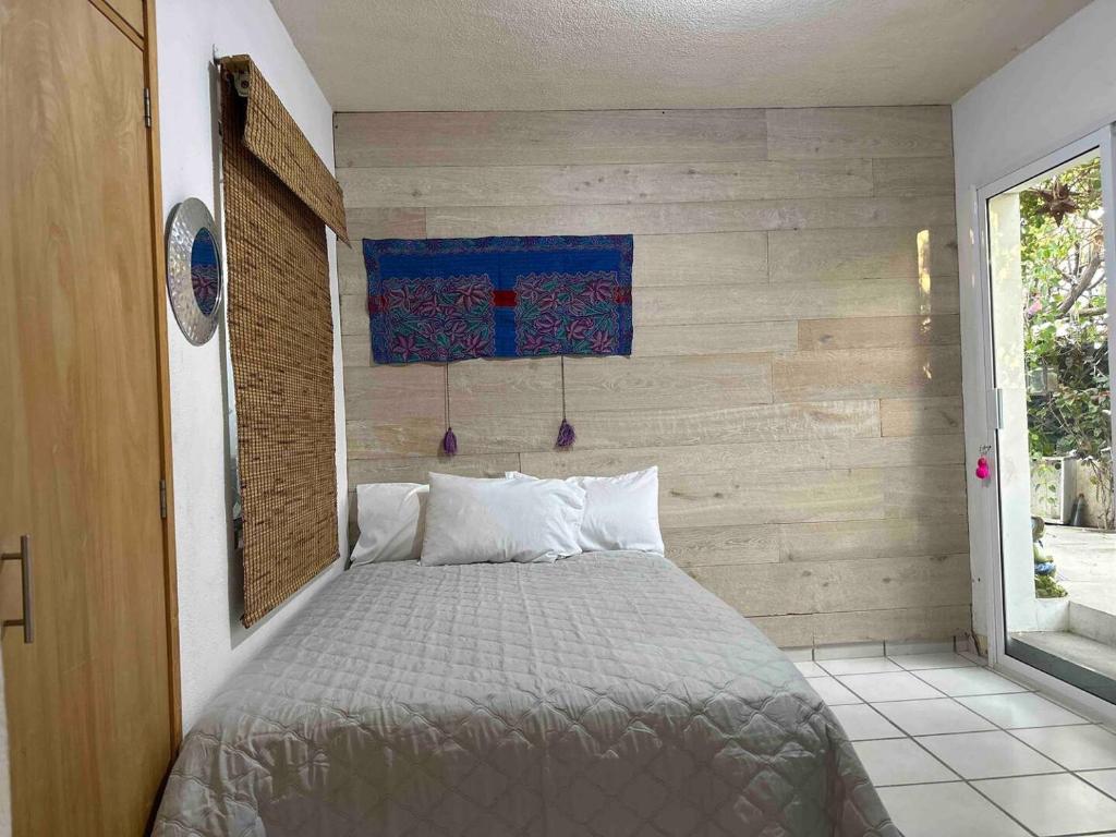 Cama en habitación con pared de madera en Oasis Casa 120, en Santa Anita
