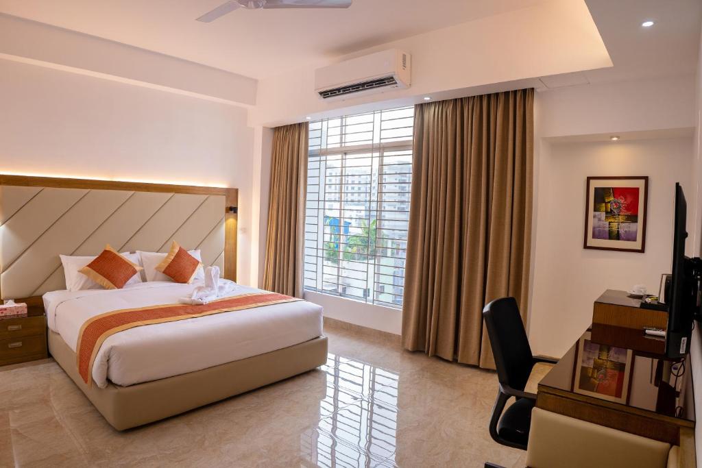 Habitación de hotel con cama, escritorio y ventana en HOTEL STUDiO23, en Dhaka