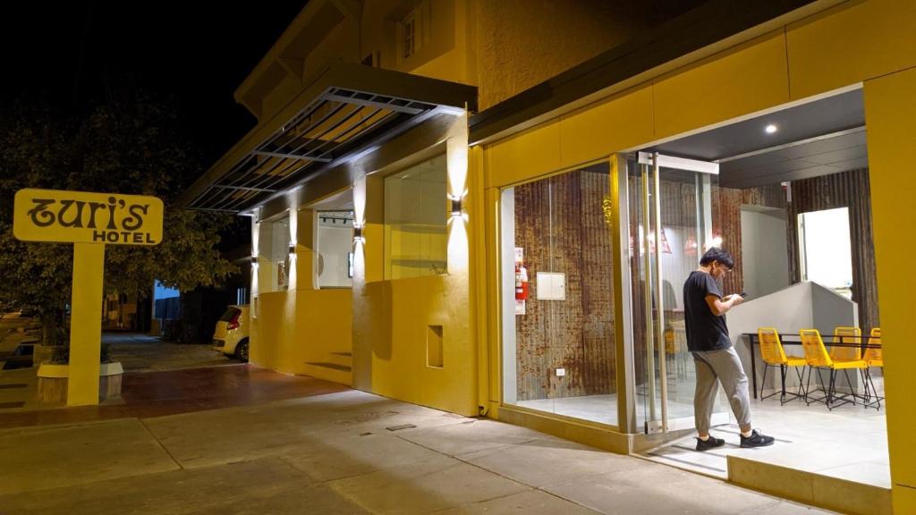 Ein Mann steht vor einem gelben Gebäude. in der Unterkunft Hotel Turis in San Rafael
