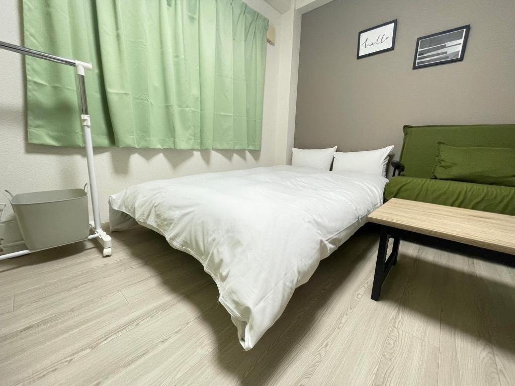 um quarto com uma cama branca e um sofá em マルチステイ大阪京橋32 em Osaka