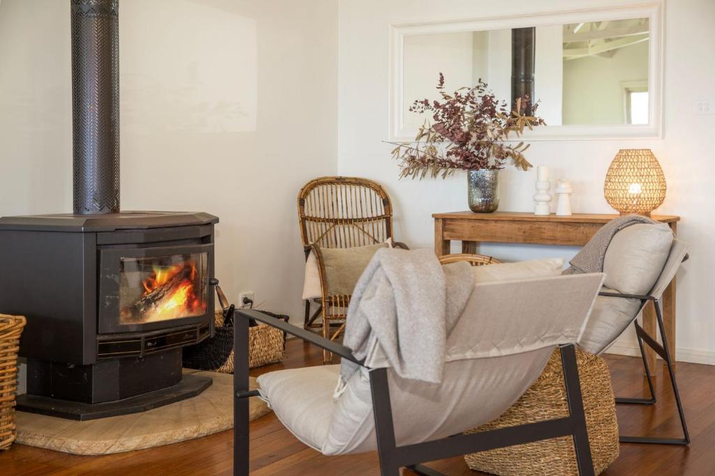 a living room with a stove and a chair and a fireplace at The Treehouse Vincentia in Vincentia