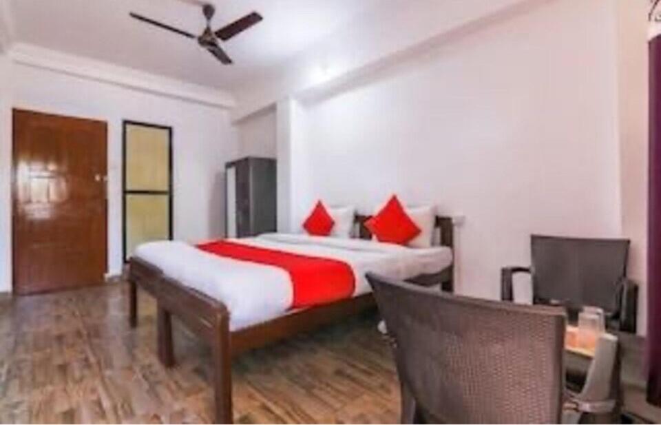 a bedroom with a large bed with red pillows at OYO Flagship 81063 Milton Inn in Baga