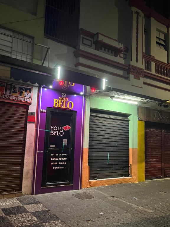 a building with two garage doors and a neon sign at Belo Motel in Belo Horizonte