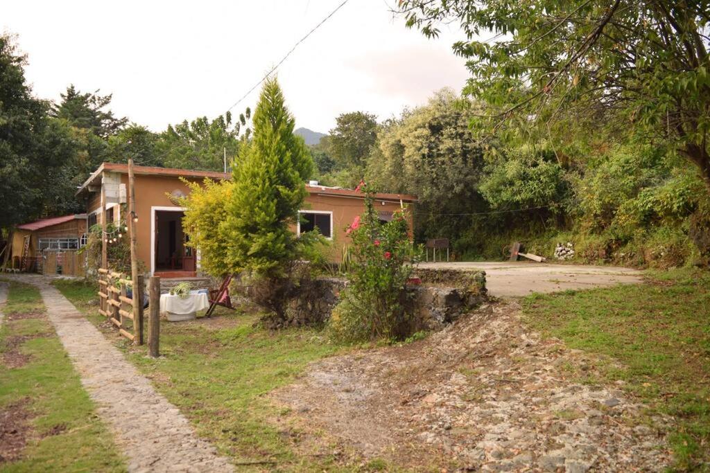 una pequeña casa en un campo al lado de una carretera en Refugio Campestre en Tepoztlán, en Santo Domingo Ocotitlán