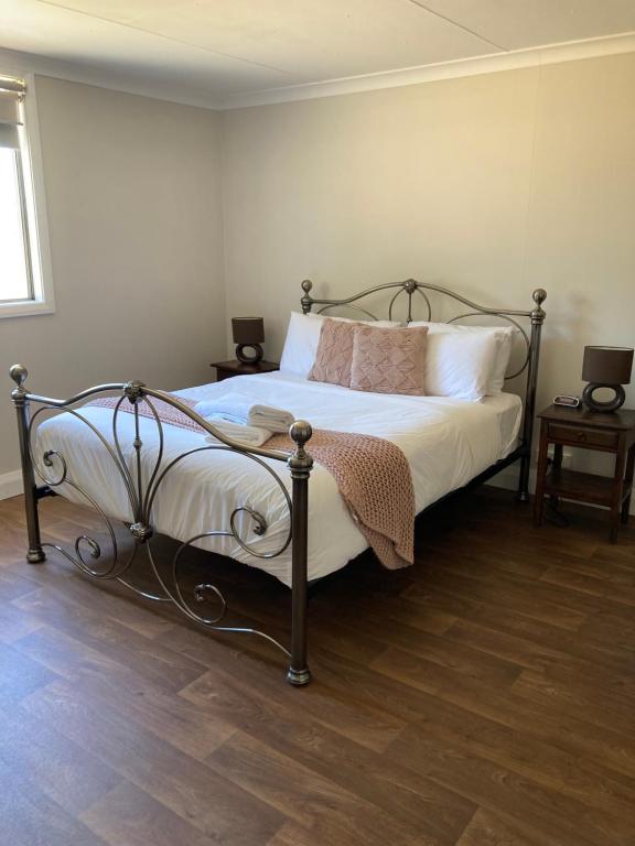 1 dormitorio con 1 cama con sábanas y almohadas blancas en The Wooly Guesthouse, en Wagin
