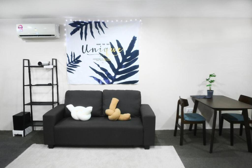 ein Wohnzimmer mit einem schwarzen Sofa und einem Tisch in der Unterkunft Private GameRoom and Cinema at The CEO Penang in Bayan Lepas