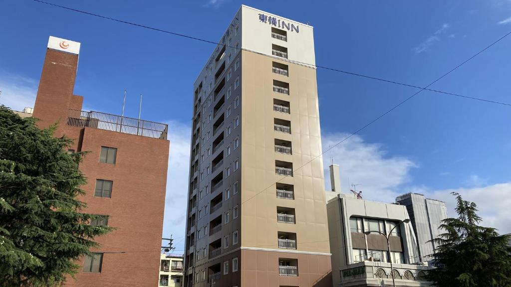 un edificio alto con un cartel encima en Toyoko Inn Tokuyama-eki Kita-guchi, en Shunan