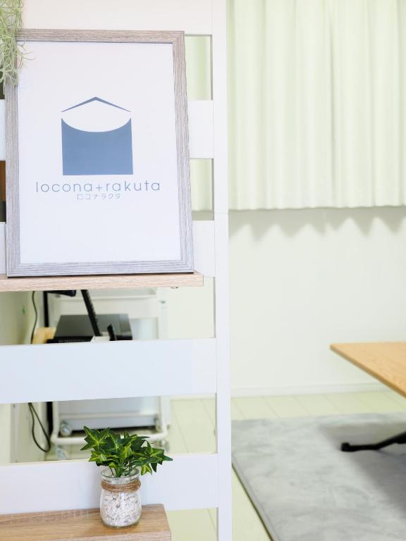 a picture frame on a shelf with a plant at locona +rakuta in Hyuga