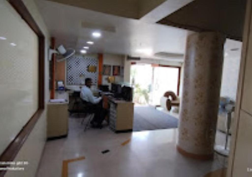 mężczyzna siedzący przy biurku w salonie w obiekcie Hotel Premier - Hotel in Saket Society Bhusawal w mieście Bhusāwal
