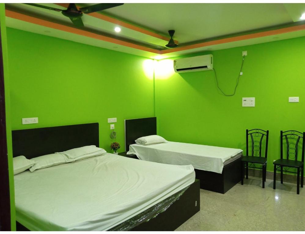 two beds in a room with green walls at Hotel Invite, Agartala in Agartala