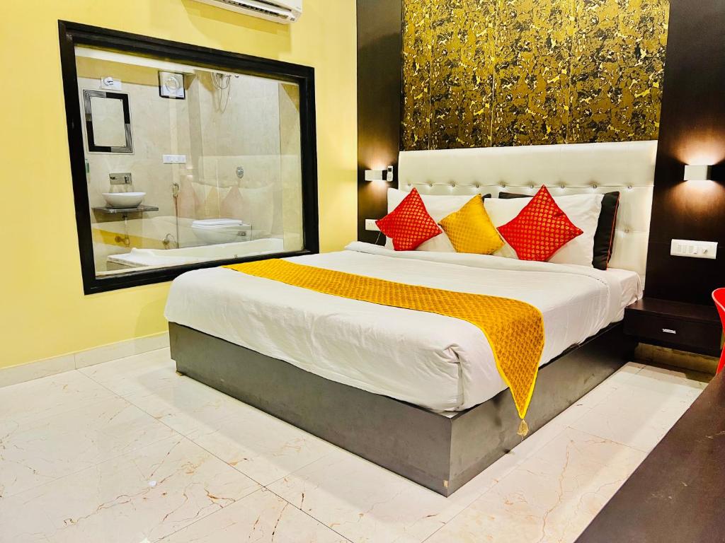 a bedroom with a large bed with red and yellow pillows at Hotel Bhagwati INN Udaipur in Udaipur