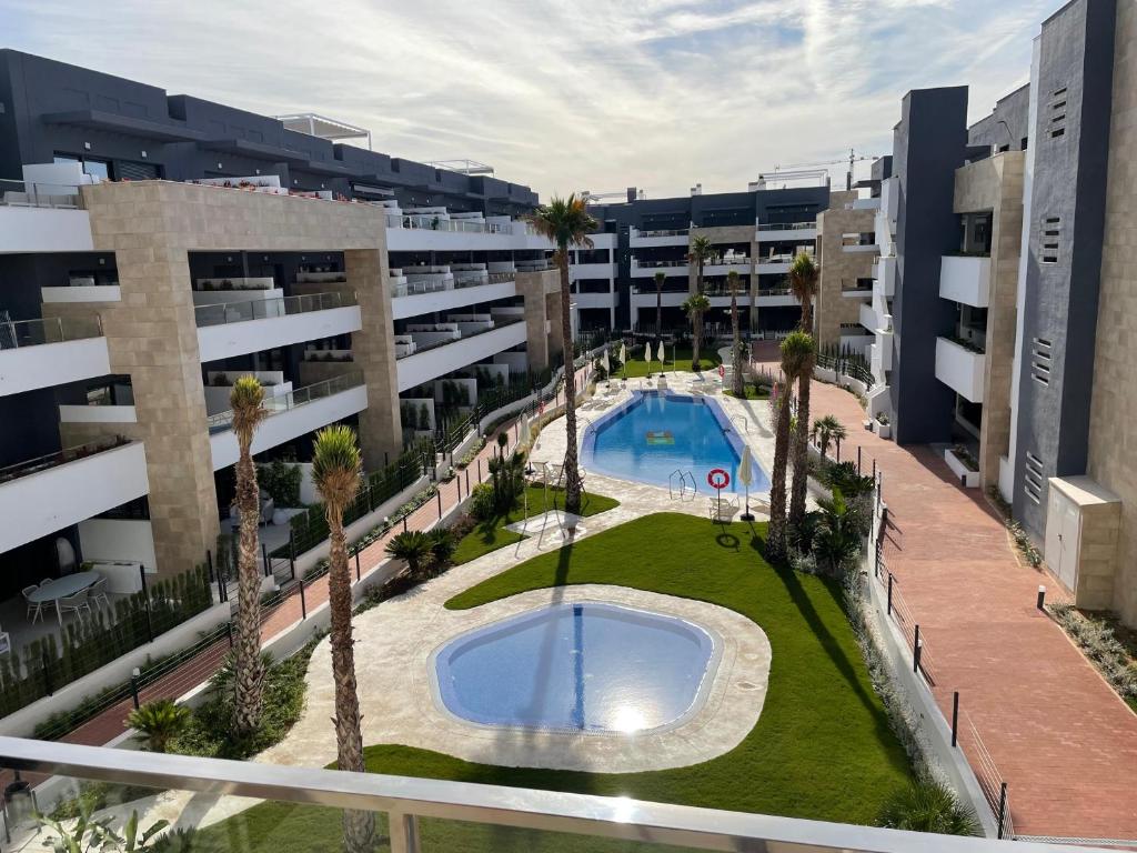 an apartment complex with a swimming pool and palm trees at Flamenca Village apartment - close to the beach and La Zenia Boulevard in Orihuela