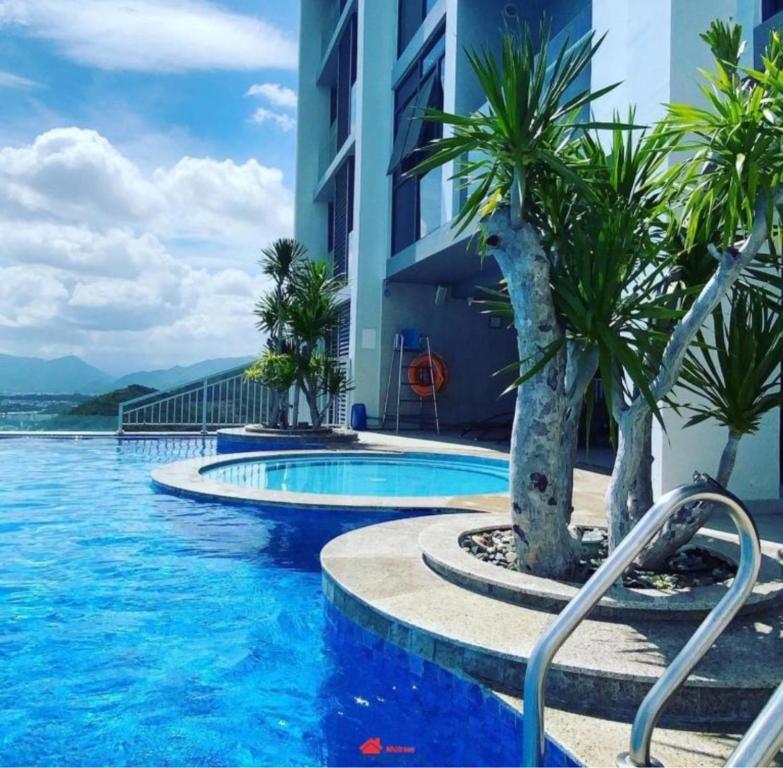 a swimming pool with palm trees next to a building at Scenia Bay Residence Nha Trang in Nha Trang