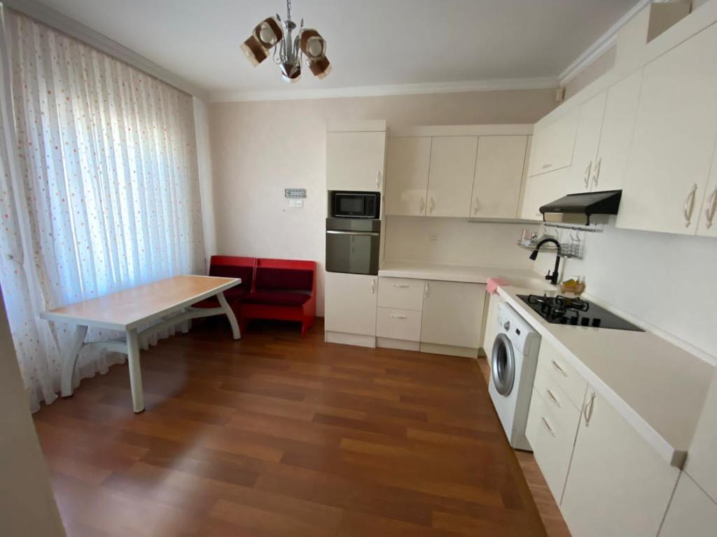 a kitchen with white cabinets and a table and a sink at Bakı, Shagan Villa in Baku