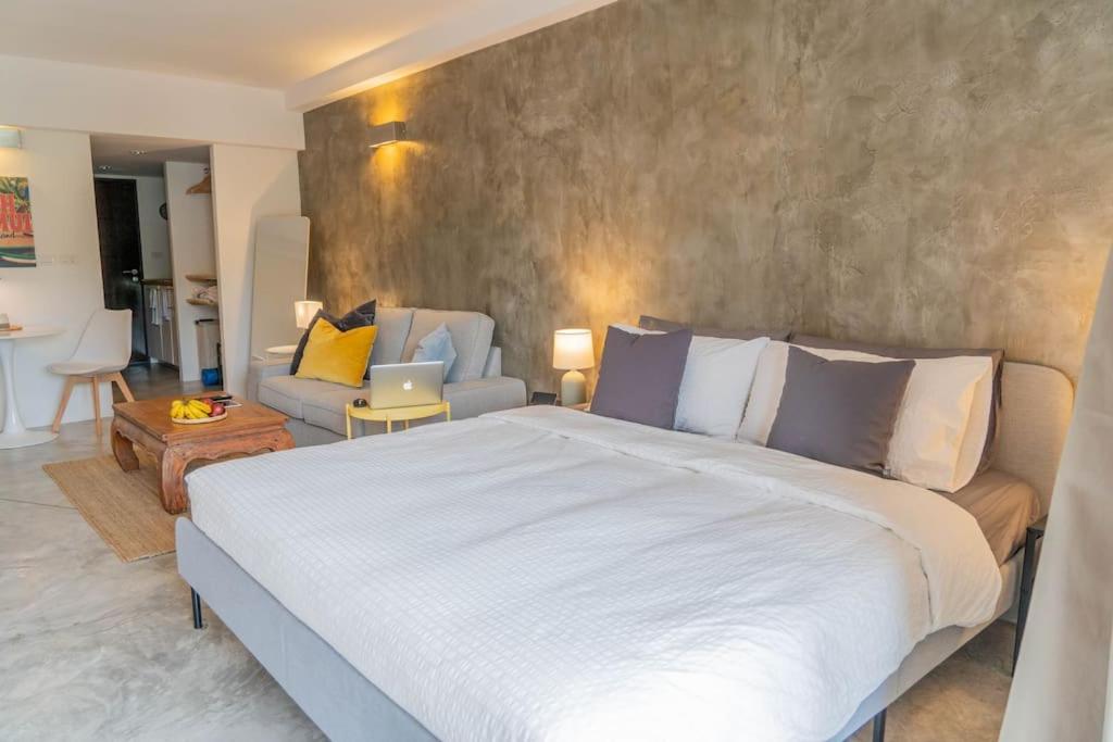 a bedroom with a large bed and a living room at [NEW] Cozy Modern Studio with Pool & Gym in Koh Samui 