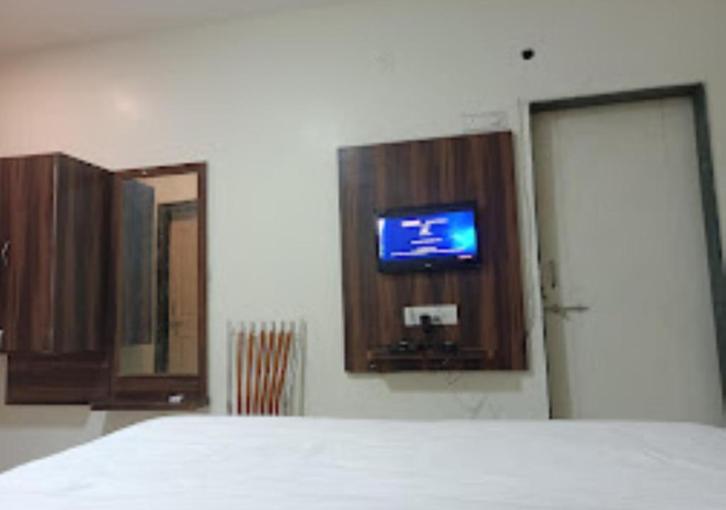 um quarto com uma cama e uma televisão na parede em Hotel Udayshree Palace Latur em Lātūr