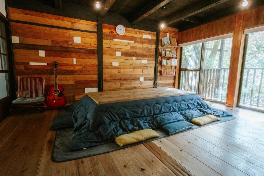 duże łóżko w pokoju z gitarą w obiekcie きよかわゲストハウス w mieście Okutama
