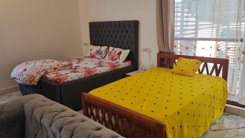 a bedroom with two beds and a table with a yellow cloth at Moderní Apartmány Raka in Nungwi
