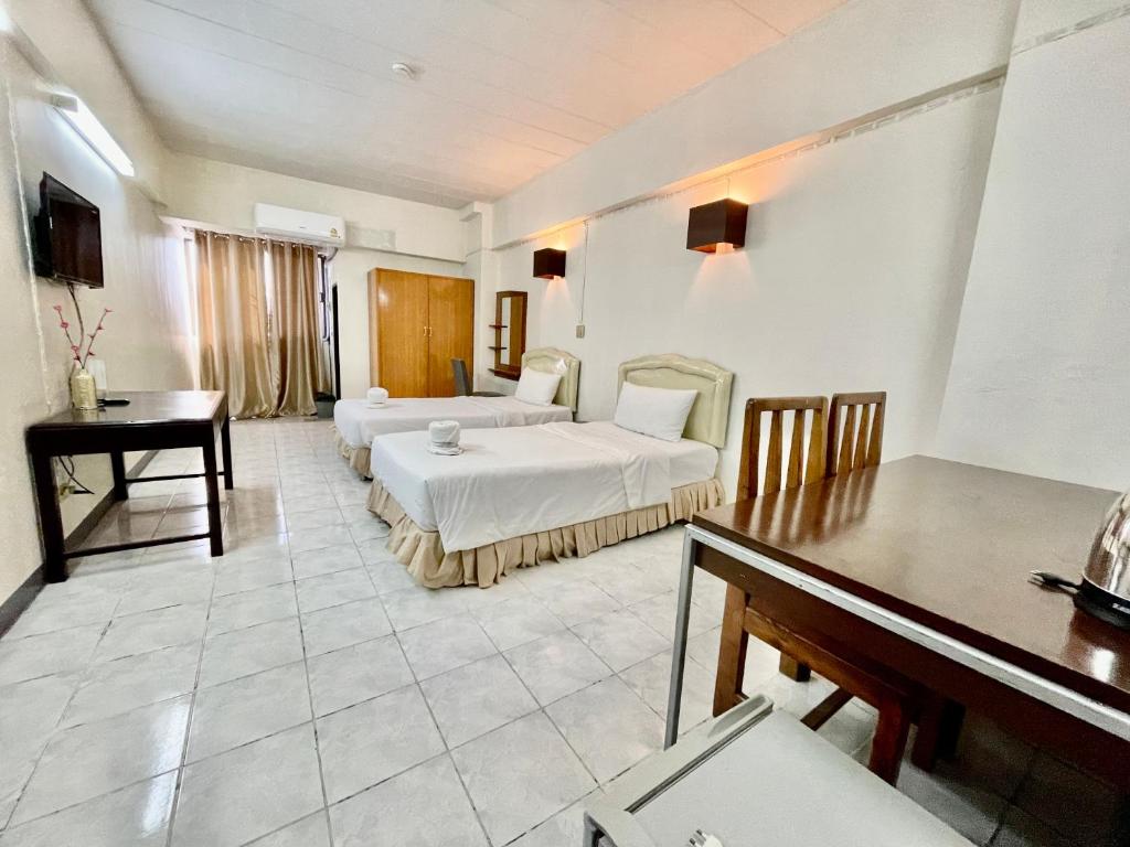 una camera con 2 letti, un tavolo e una scrivania di โรงแรมวินบางนา Win Bangna Hotel a Bang Na