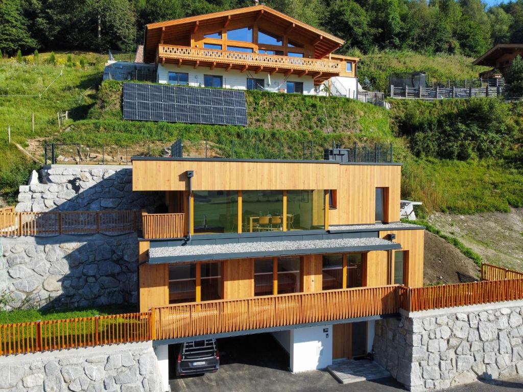 une maison avec des panneaux solaires sur le côté d'une colline dans l'établissement Exclusive chalet with sauna and unique view of the glacier, à Neukirchen am Großvenediger